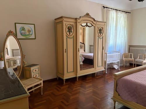 Camera elegante della Villa Mirano B&B a Piossasco con armadio in legno intarsiato, specchio e mobili d'epoca