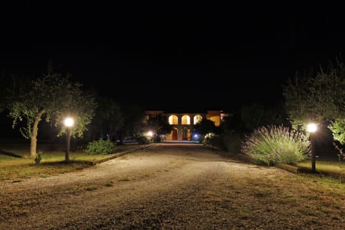 Agriturismo Buriano entrance at night, illuminated driveway with olive trees and rustic building in Lubriano, Italy