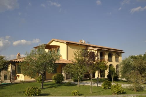 Agriturismo Buriano farmhouse in Lubriano with yellow walls, terracotta roof, olive trees, and manicured gardens