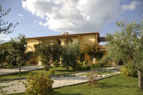 Agriturismo Buriano in Lubriano features a yellow farmhouse surrounded by olive trees and green grounds