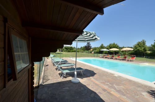 Swimming pool with loungers and umbrellas at Agriturismo Buriano in Lubriano, Italy