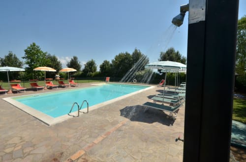 Agriturismo Buriano pool area in Lubriano with lounge chairs, umbrellas, and outdoor shower