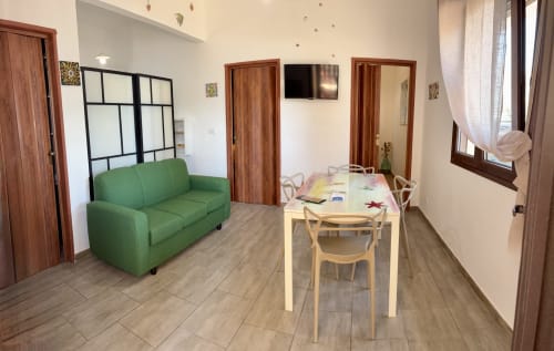 Bright apartment living area with green sofa, wooden dining table, and sea views at Noemi Holiday House, Agnone Bagni