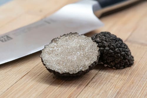 Truffe noire fraîchement tranchée sur planche à découper en bois avec couteau à Vila Cabanes 46