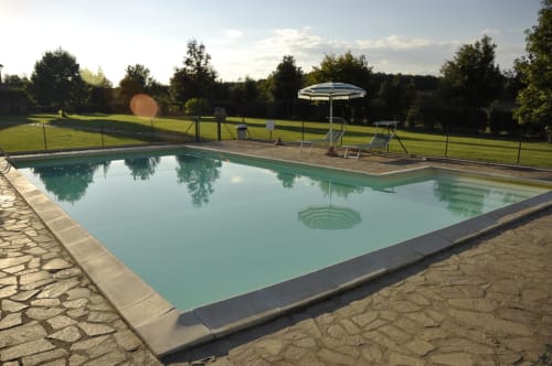Swimming pool at Agriturismo Buriano in Lubriano with lounge chairs, umbrella, and green countryside views