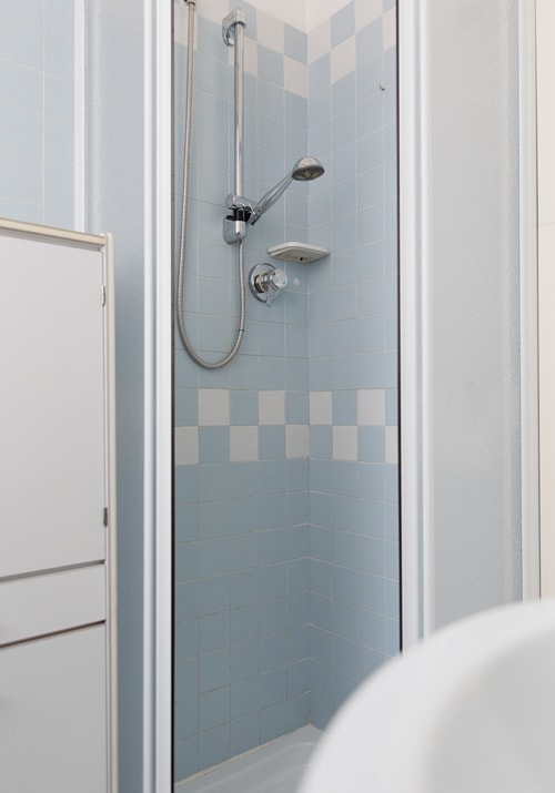 Modern shower stall with light blue tiles and white accents at Cristallo Apartment in Ravenna, Italy