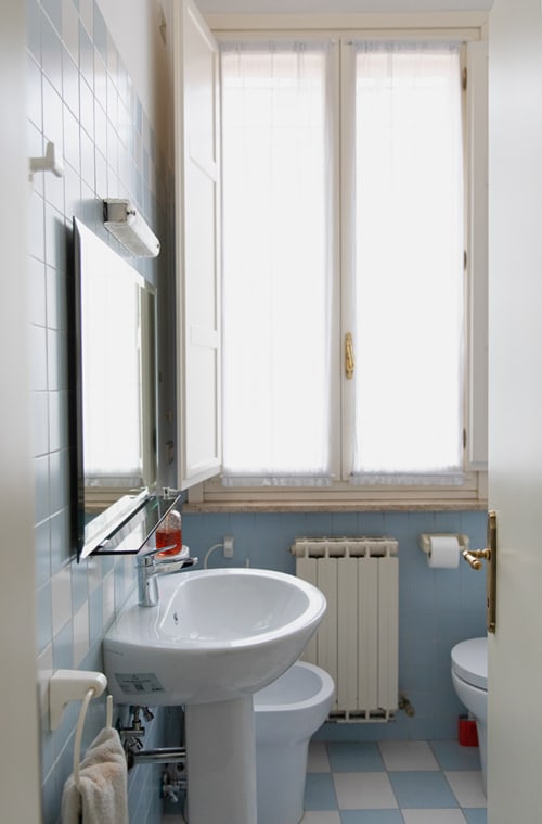 Clean bathroom at Cristallo Apartment in Ravenna with pedestal sink, toilet, and large window with natural light