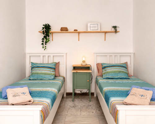 Twin beds with turquoise striped bedding in a bright bedroom at Alojamientos vacacionales La Aldea, Cercadillos, with wooden