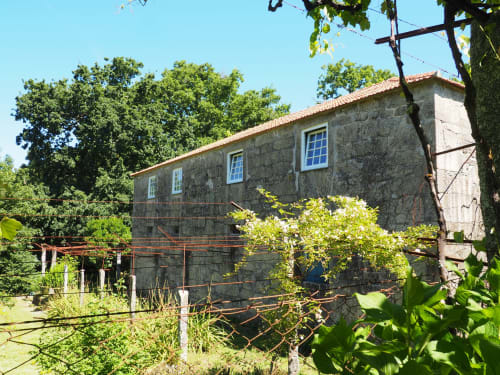 Casa de pedra na Quinta da Coutada Agroturismo em Arcos de Valdevez com janelas azuis e vegetação exuberante
