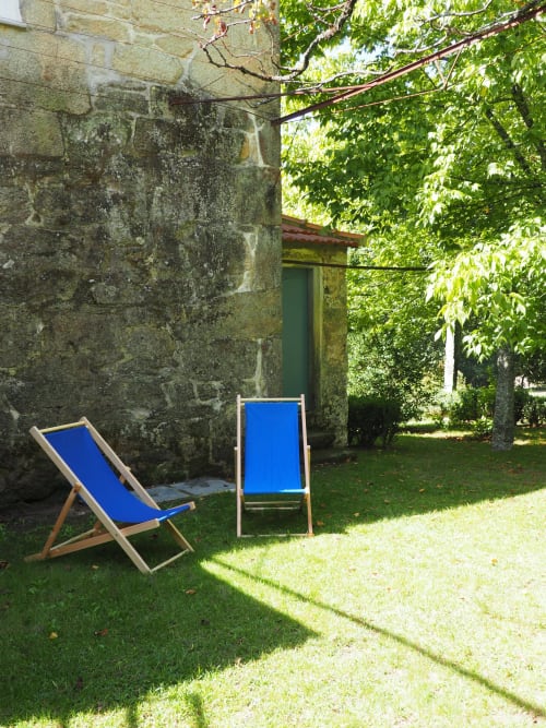 Duas espreguiçadeiras azuis na relva junto a parede de pedra musgenta na Quinta da Coutada, Portugal