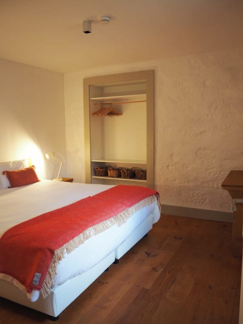 Quarto aconchegante na Quinta da Coutada com cama branca, manta vermelha, assoalho em madeira e roupeiro embutido em Arcos de Valdevez