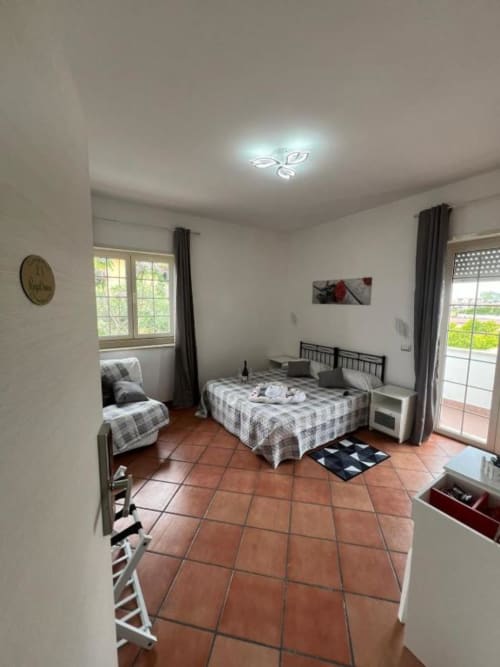 Spaziosa camera matrimoniale presso Royal House Fiumicino con pavimenti in cotto, letto matrimoniale, angolo cottura e porte in vetro sulla terrazza