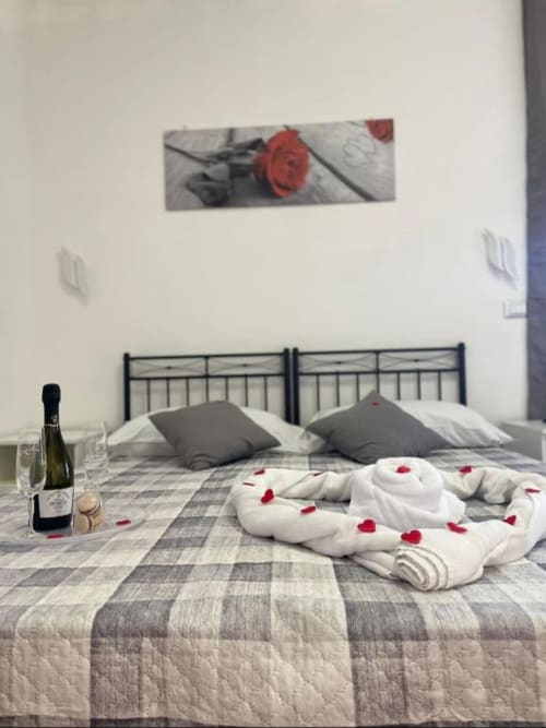 Camera matrimoniale romantica al Royal House Fiumicino con petali di rosa, champagne e arredamento moderno