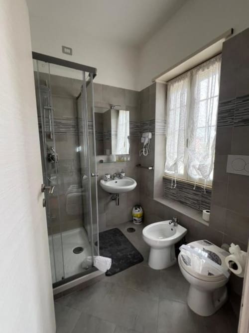 Bagno moderno della Royal House Fiumicino con box doccia, doppio lavabo, bidet e finestra a Fiumicino