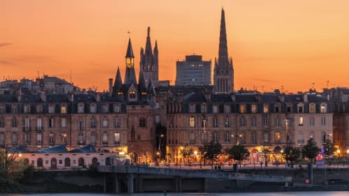 Skyline de Bordeaux au coucher de soleil avec l'architecture historique et les flèches reflétées dans l'eau