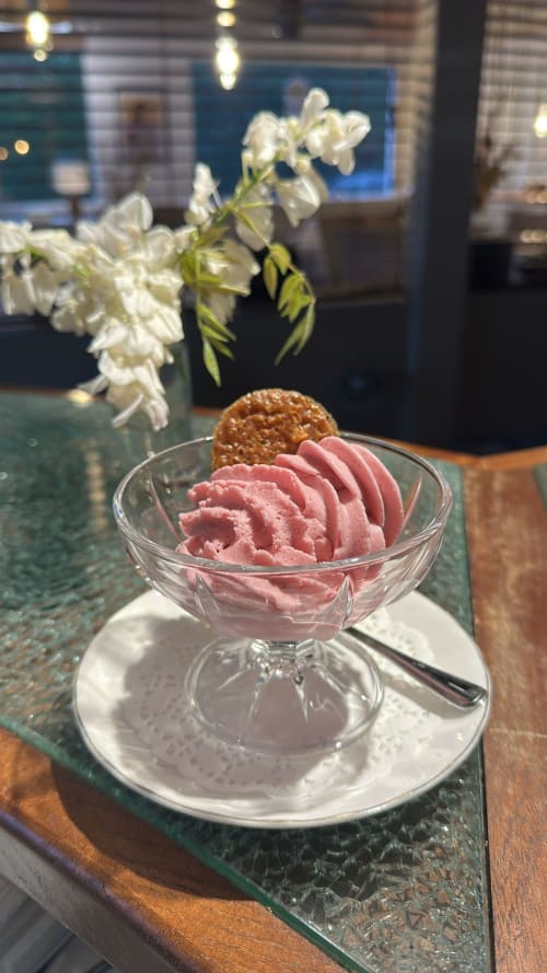 Glace rose dans une coupe en cristal au salon de thé du Boïate Hôtel à Arès, avec fleurs blanches et intérieur moderne élégant