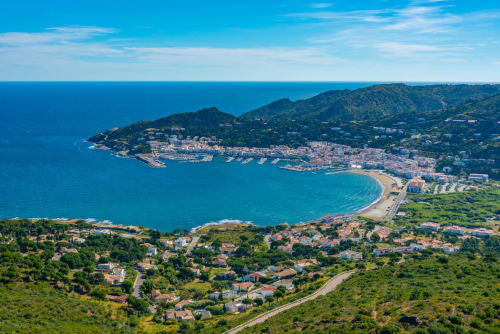 Vista aérea de Perelada con aguas azules del Mediterráneo, playa de arena y vegetación en las laderas cerca del Hotel Can Carbó