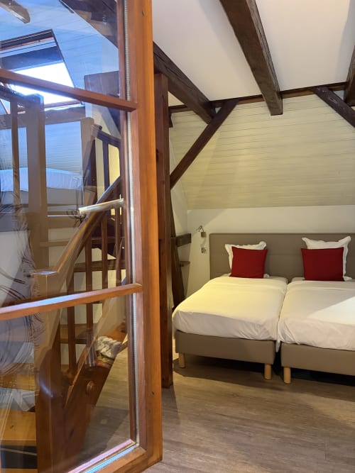 Hôtel de l'Ange Niedermorschwihr : Chambre Familiale avec lits jumeaux, oreillers rouges, poutres en bois et porte vitrée