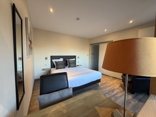 Chambre Tradition du Hôtel de l'Ange : chambre double avec lit queen-size, lampe et parquet à Niedermorschwihr