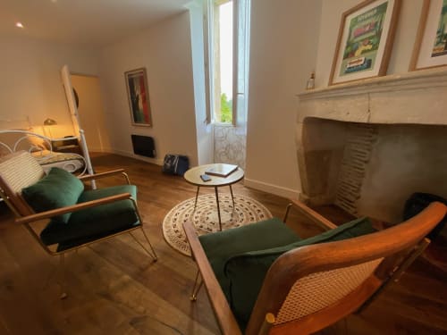 Vintage 1930s-style room at Le Prieuré with teak chairs, green cushions, fireplace, and wooden floors in