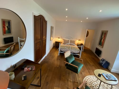 Spacious 1930s-style bedroom at Le Prieuré de Saint-Pierre with wrought iron bed, green velvet chairs, and wooden floors