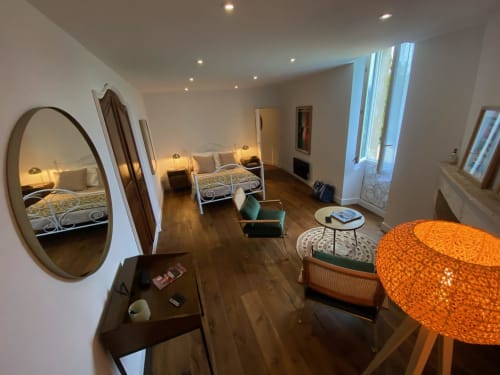 Spacious 30's style bedroom at Le Prieuré de Saint-Pierre B&B with dual beds, orange pendant lamp, round mirror, and hardwood