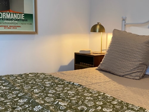Vintage 1930s-style bedroom at Le Prieuré de Saint-Pierre with brass lamp, patterned bedding, and neutral pillows