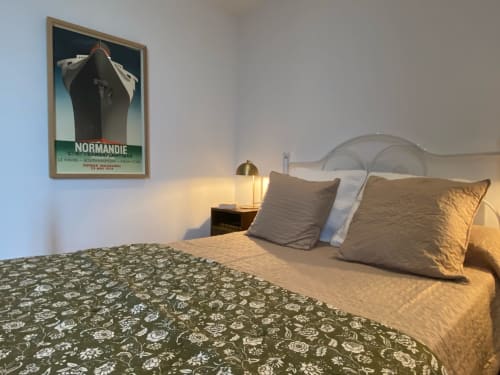 Vintage Normandie poster above bed with gold pillows at Le Prieuré de Saint-Pierre, Saint-Pey-de-Castets