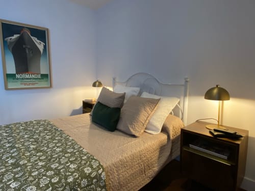 Art deco bedroom at Le Prieuré de Saint-Pierre with vintage Normandie poster, brass lamps, and pool view in