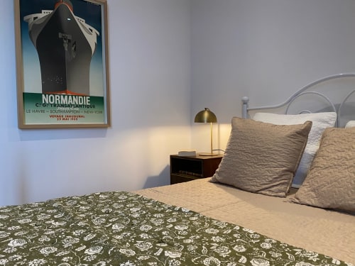 1930s-themed bedroom at Le Prieuré de Saint-Pierre with vintage ship poster, brass lamp, and patterned bedding