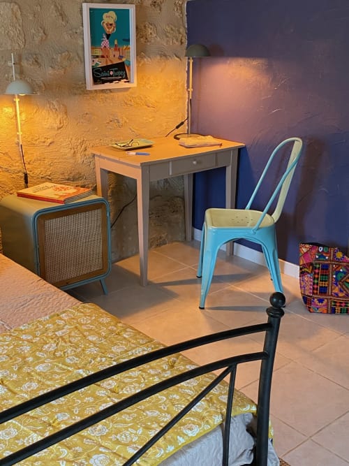 Vintage 1950s-style bedroom at Le Prieuré with blue metal chair, desk, warm lighting, and garden view in Saint-Pey-de-Castets