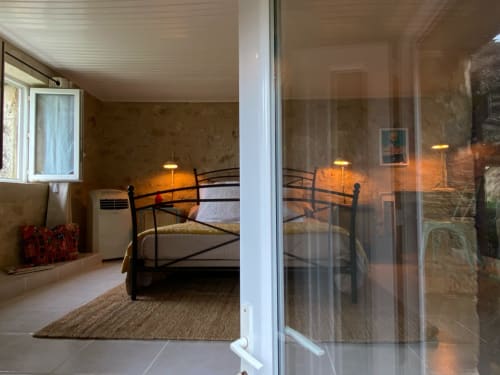 Chambre 50's at Le Prieuré with metal bed, warm lighting, garden view through glass doors, and patio access in