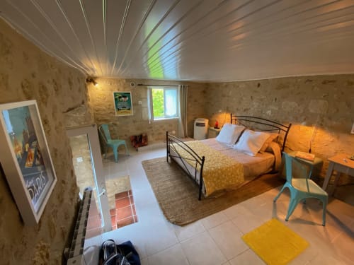 1950s-themed bedroom at Le Prieuré with black metal bed, turquoise chairs, garden view window, and warm lighting