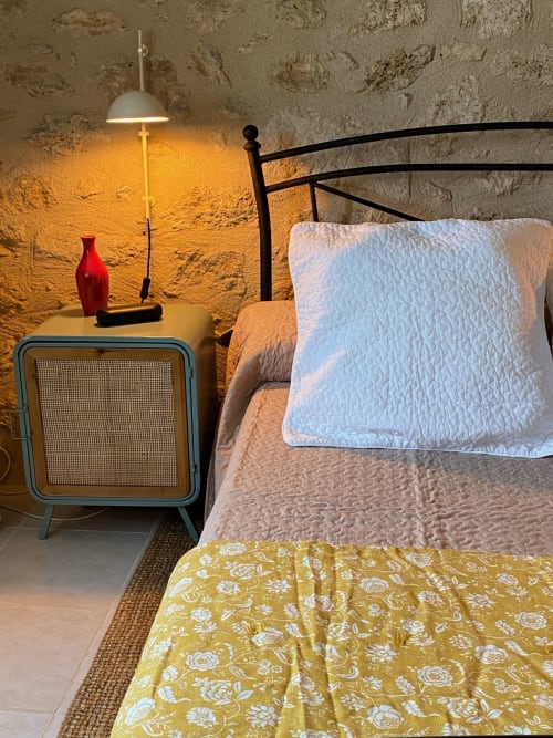 Cozy 1950s-style bedroom at Le Prieuré de Saint-Pierre with vintage radio nightstand, metal bed frame, white pillow, and warm