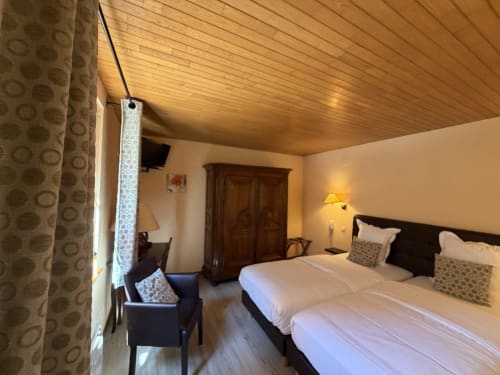 Chambre double de l'Hôtel de l'Ange à Niedermorschwihr avec plafond en bois, fauteuil et armoire en bois