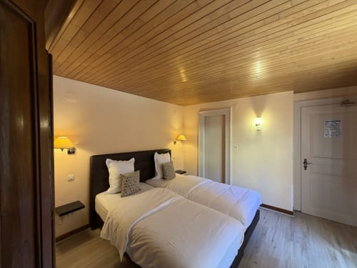 Deux lits jumeaux dans une chambre moderne de l'Hôtel de l'Ange à Niedermorschwihr avec plafond en bois et décoration contemporaine