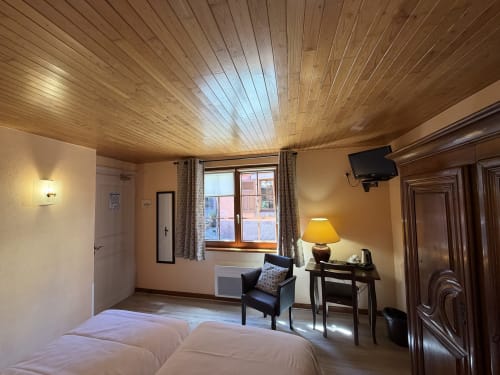 Chambre Classique Twin Hôtel de l'Ange avec plafond en bois, lits jumeaux, fauteuil, bureau et fenêtre avec vue