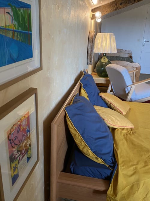 Cozy bedroom at Le Prieuré de Saint-Pierre with twin beds, yellow bedding, blue sleeping bags, desk lamp, and framed artwork