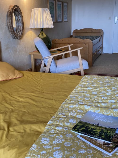 Bedroom at Le Prieuré de Saint-Pierre with twin beds, floral bedding, lamp, chair, and garden views in Saint-Pey-de-Castets.