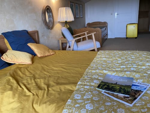 Spacious bedroom at Le Prieuré with yellow bedding, blue accents, wooden furniture, and garden view at this