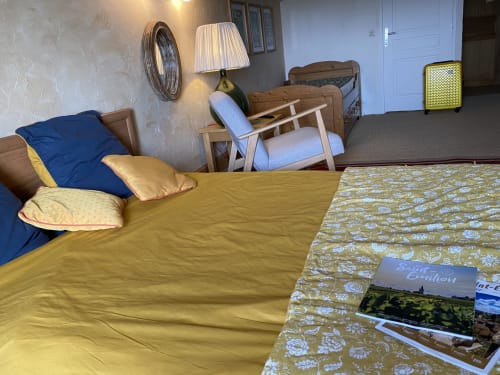 Cozy bedroom at Le Prieuré de Saint-Pierre with yellow bedding, blue pillows, wooden furniture, and garden view in