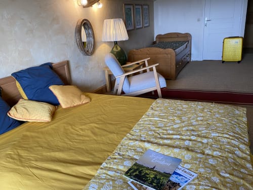 Chambre Le Prieuré au Prieuré de Saint-Pierre avec literie jaune, lit en bois et vue sur le jardin