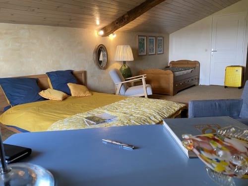 Spacious bedroom at Le Prieuré de Saint-Pierre B&B with yellow bedding, wooden beams, dual beds, desk, and garden view in