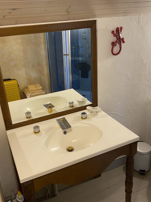 Modern bathroom vanity with white sink, mirror, and gold fixtures in Le Prieuré de Saint-Pierre guesthouse, France
