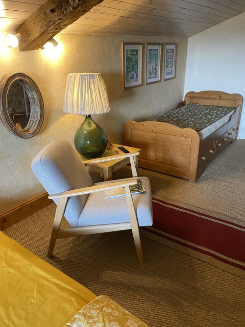 Cozy bedroom at Le Prieuré de Saint-Pierre with wooden bed, armchair, lamp, and garden view