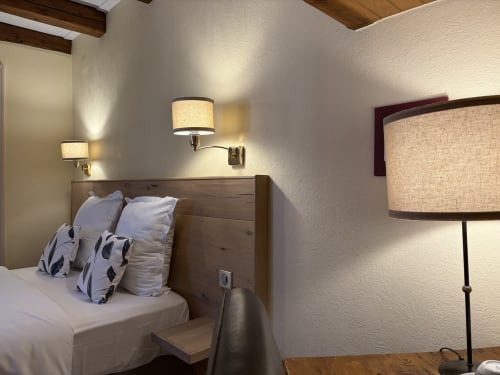Chambre double cosy au Hôtel de l'Ange à Niedermorschwihr avec tête de lit en bois, literie blanche, appliques murales et lampadaire