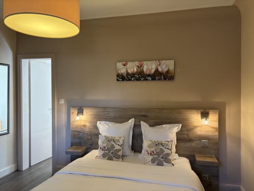 Chambre moderne de l'Hôtel de l'Ange avec tête de lit en bois, linge blanc et tableau de tulipes à Niedermorschwihr