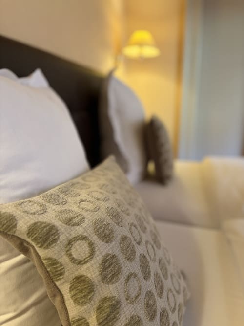 Chambre d'hôtel à l'Hôtel de l'Ange avec literie motifs, oreillers et éclairage ambiant chaleureux de lampe de bureau