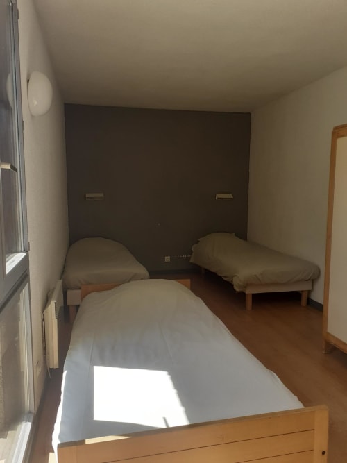 Chambre sextuple au Centre Sportif d'Altitude de Briançon avec trois lits simples et tête de lit foncée