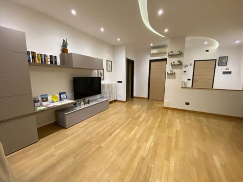 Soggiorno moderno presso MiSaNi Apartments con pavimenti in legno, TV, mobili beige e luci contemporanee al soffitto